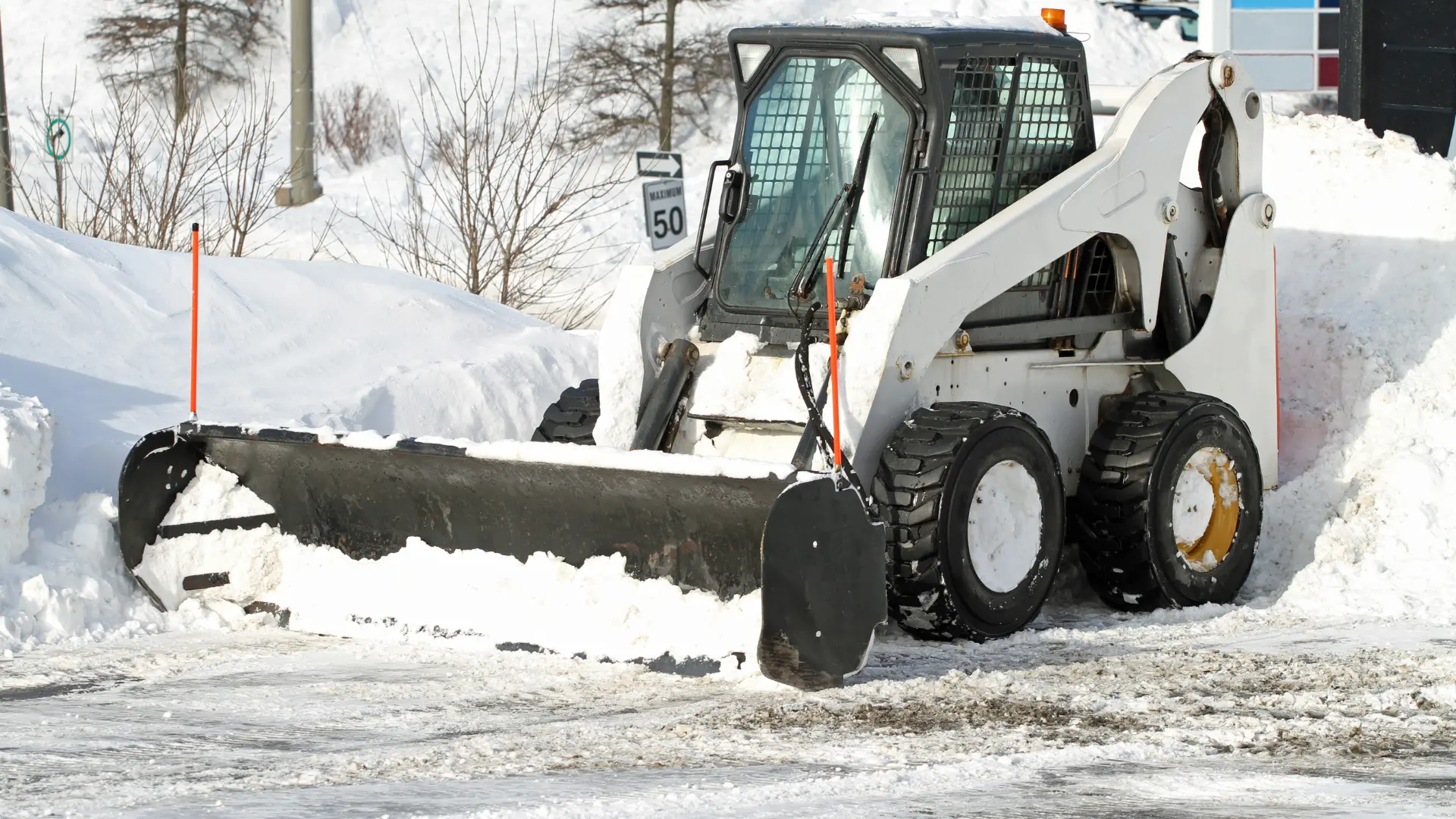 white snow plow removing snow